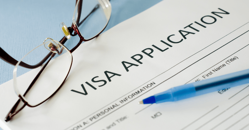 A visa application and a pen and pair of contacts placed on it. 